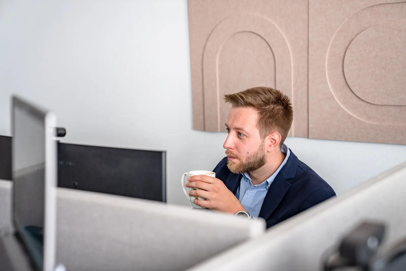 Mitarbeiter genießt eine Kaffeepause am Schreibtisch im Cogitaris-Büro