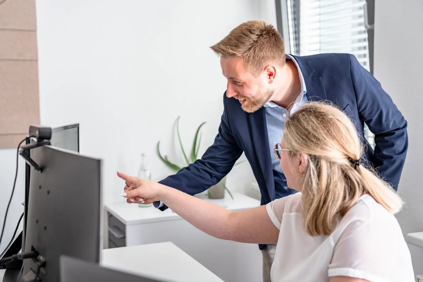 Kollegin und Kollege besprechen gemeinsam Auswertungsergebnisse am Monitor